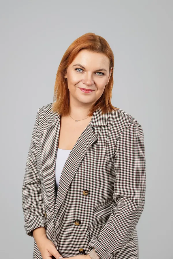 Moters portretas languotu švarku pilkame studijos fone